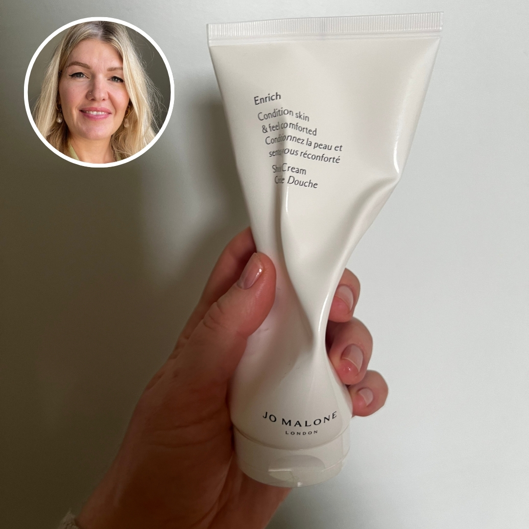 Hand holding an empty bottle of Jo Malone London Enrich Shower Cream, with circular photo of Fiona McKim in top left corner
