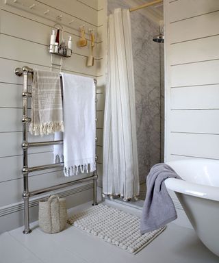 Cream bathroom with marble shower and towels hanging on a towel rack
