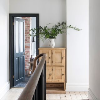 Navy blue door and doorframe, wooden cabinet, houseplant, banniser