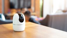 Indoor camera on wooden table in living room with blurred family in background