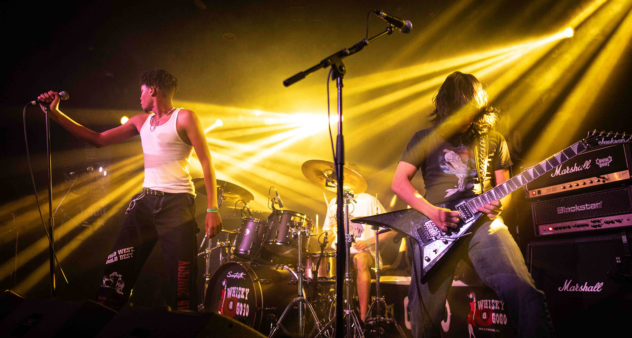 Chained Saint perform live with frontman Sean Sterling wearing a white vest and guitarist Ethan Kahn wearing black and playing a black Jackson Rhoads.