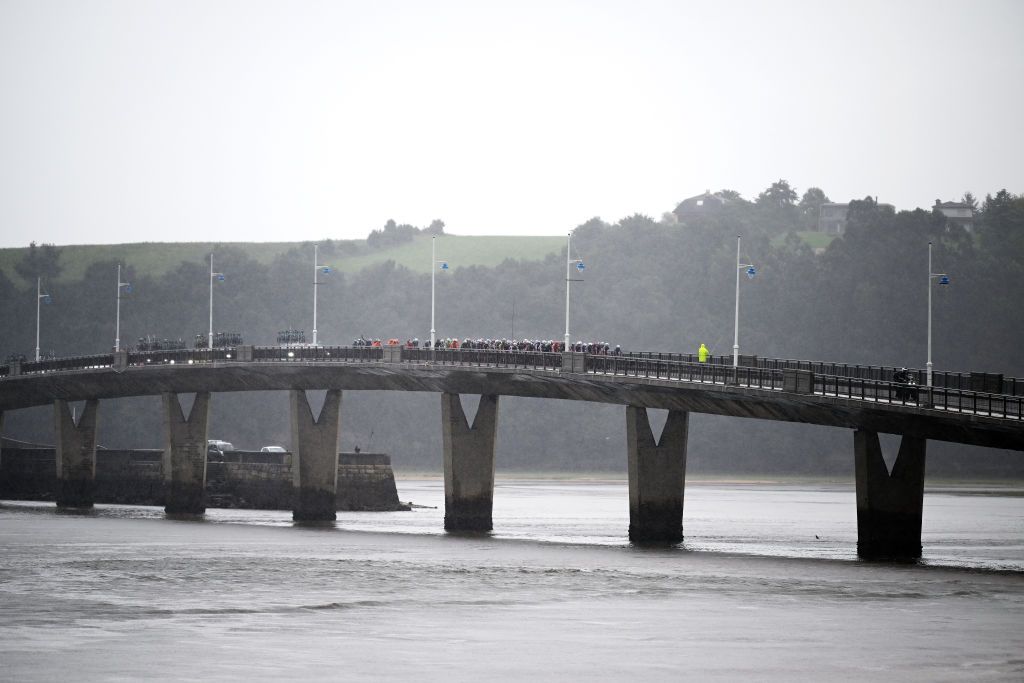 SANTANDER SPAIN SEPTEMBER 04 A general view of the peloton crossing a bridge under heavy rain during the La Vuelta 79th Tour of Spain 2024 Stage 17 a 1415km stage Arnuero to Santander UCIWT on September 04 2024 in Santander Spain Photo by Dario BelingheriGetty Images