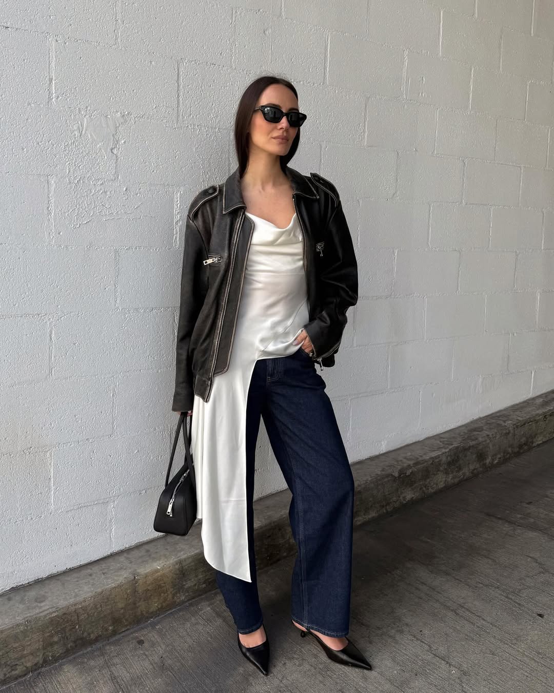 Livv Perez wearing a leather jacket, silk shirt, indigo jeans, and slingback heels