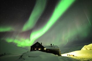 Auroras Glow Over Hotel in Swedish Lapland by Chad Blakley
