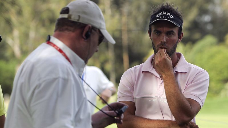 A golfer is seen being awarded a penalty by a referee