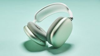 Apple AirPods Max headphones in silver finish on a minty teal background
