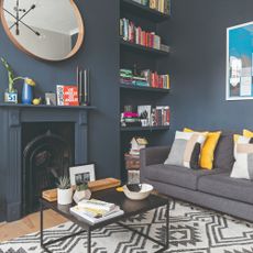 A charcoal grey-painted living room with built-in shelves in an alcove and a grey sofa