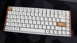 A Keychron K2 HE gaming keyboard with a wood finish and white keycaps with RGB enabled.