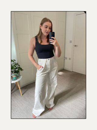 Frau trägt Tanktop und weiße Jeans