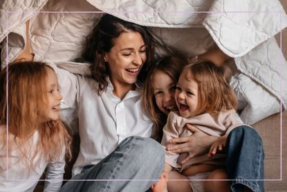 Mum laughing with her three children under a blanket
