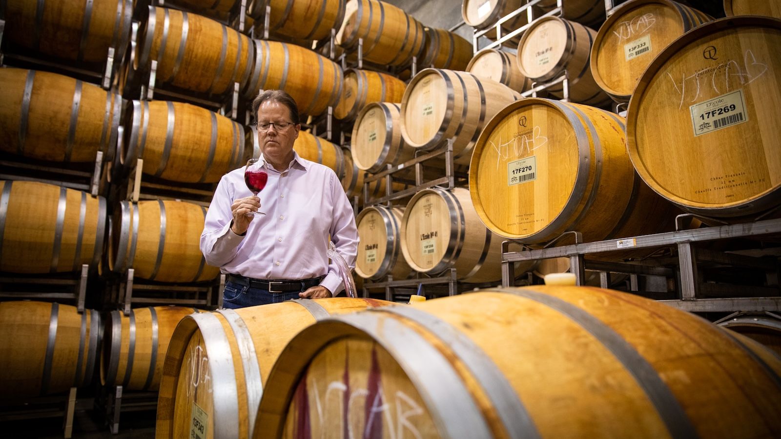 L'Ecole No 41 owner Marty Clubb holding a glass of red wine in the winery's barrel cellar