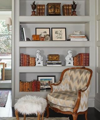 muted blue bookshelf corner with an antique chair and stool
