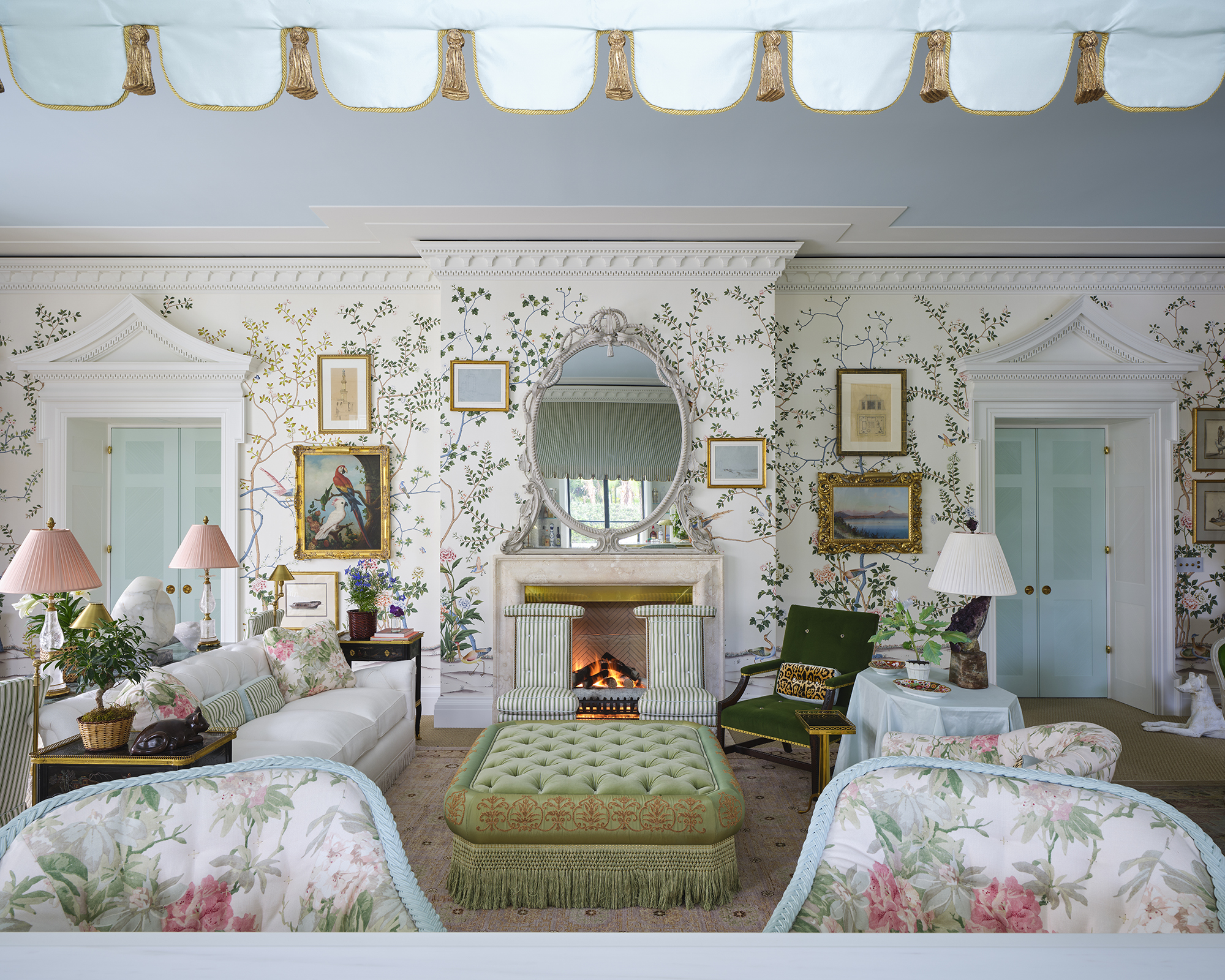 large living room with white walls covered in a botanical motif and powder blue ceilings. The furniture is arranged in a symmetrical layout