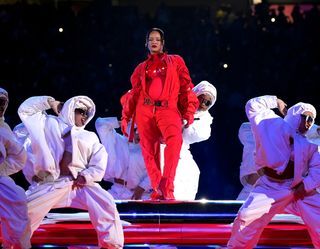 Rihanna wears all red and is surrounded by male dancers wearing white