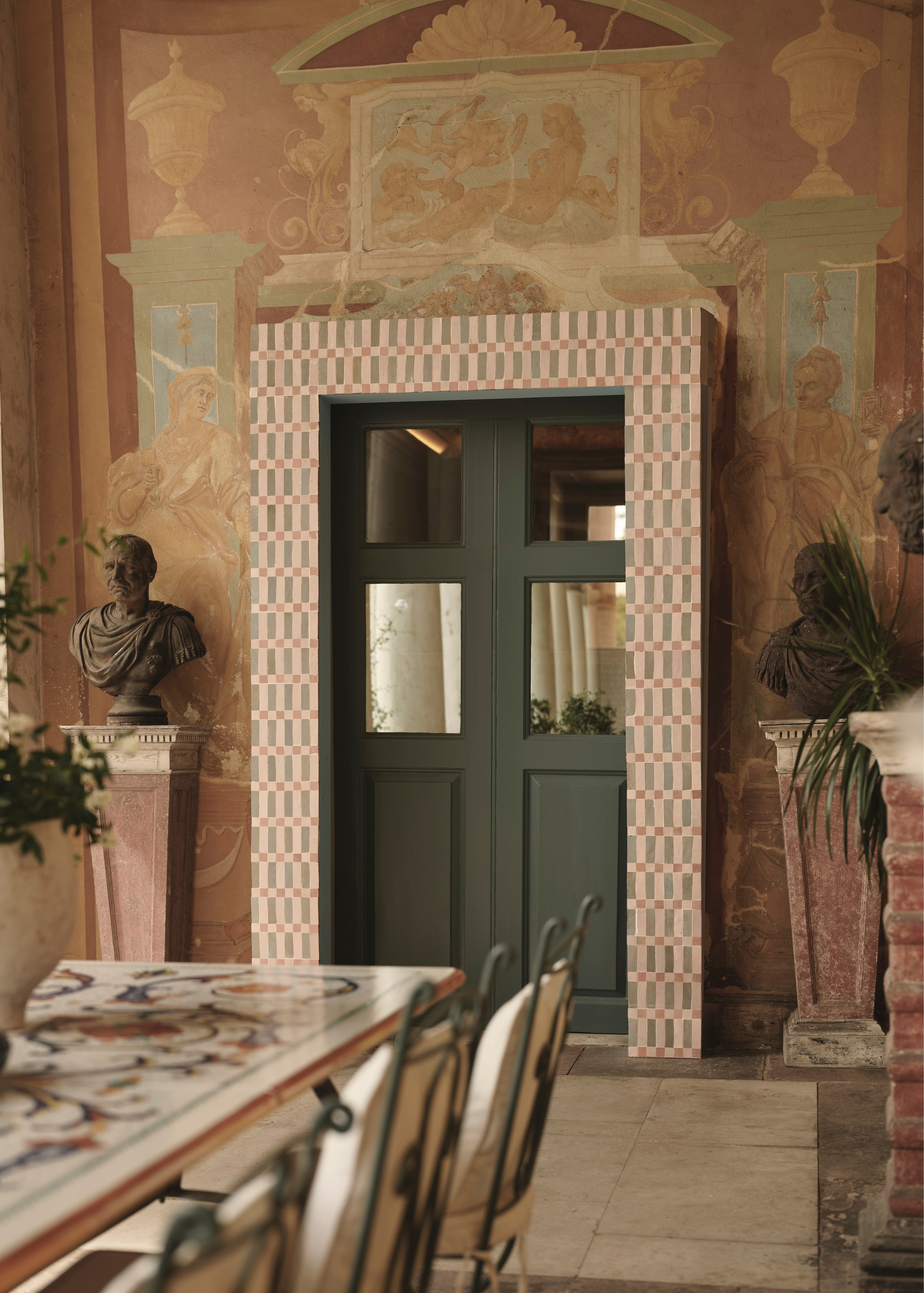 a tiled doorway and a dramatic and elaborate room with busts and marble and frescoed walls