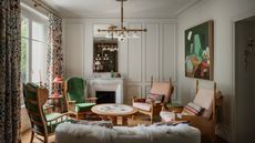 Eclectic living room with wood armchairs and round coffee table, abstract art and fluffy sofa