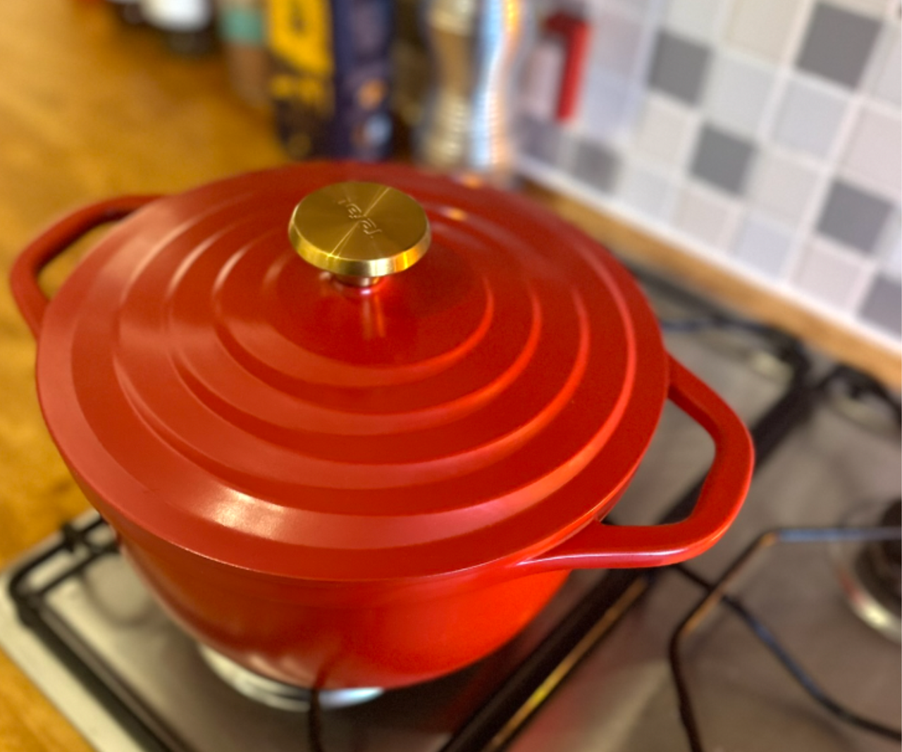 A red Tefal Dutch Oven with a gold knob lid, on a gas stove.