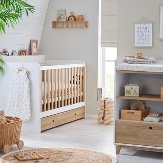 Nursery with white walls and white wood floor, cot bed and changing table
