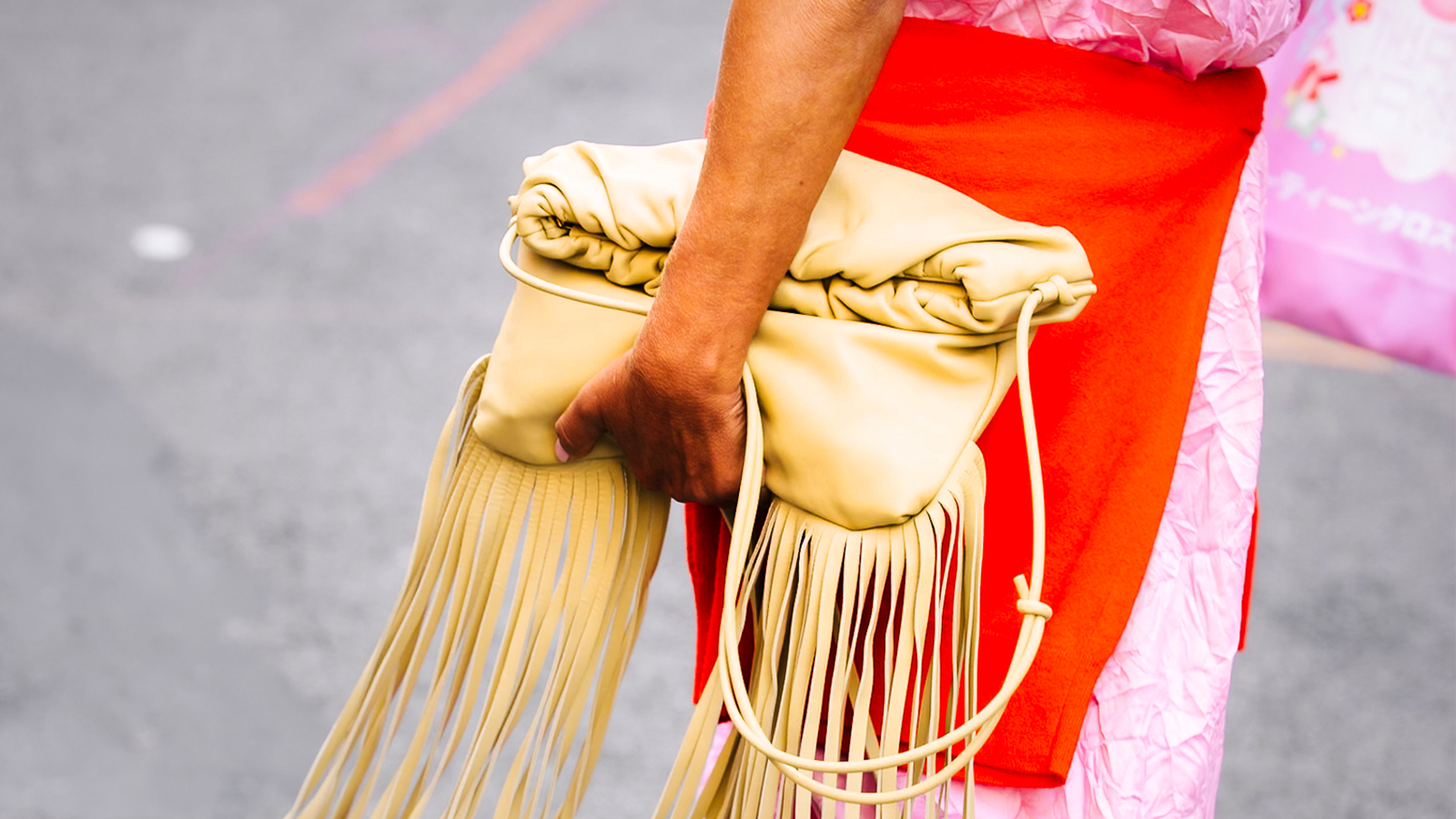 yellow fringe leather clutch with a stylish orange sweater and pink skirt 