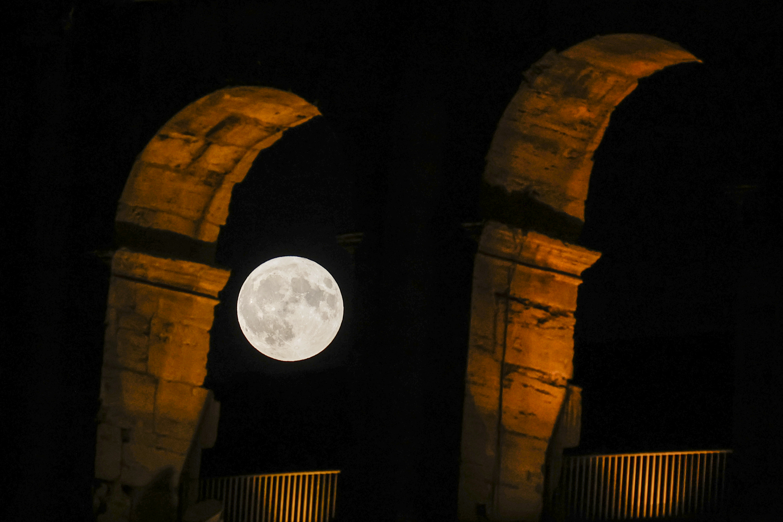 Full moon between two large stone arches.