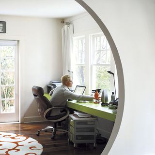 home office with white wall green desk window and wooden flooring