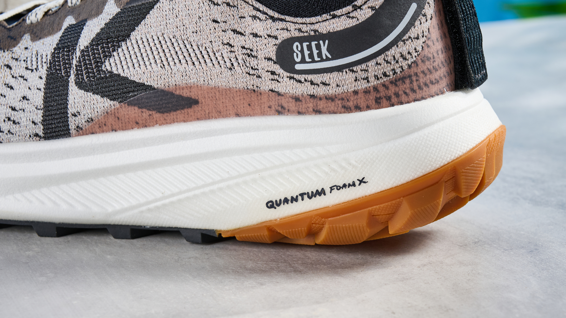 the keen seek trail shoes in brown, black, and beige photographed against the blue tom's guide background