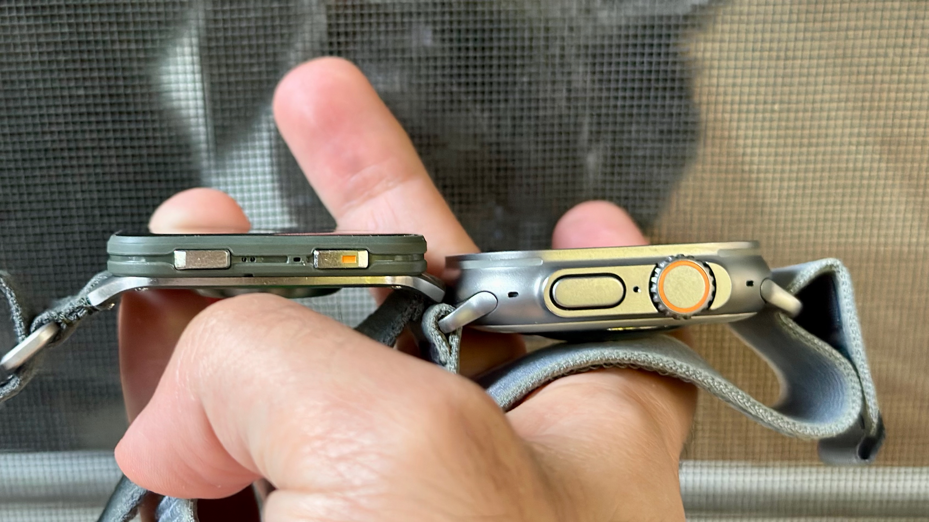 A side view of the Garmin Venu X1 (left) and Apple Watch Ultra 2 (right) held in one hand.