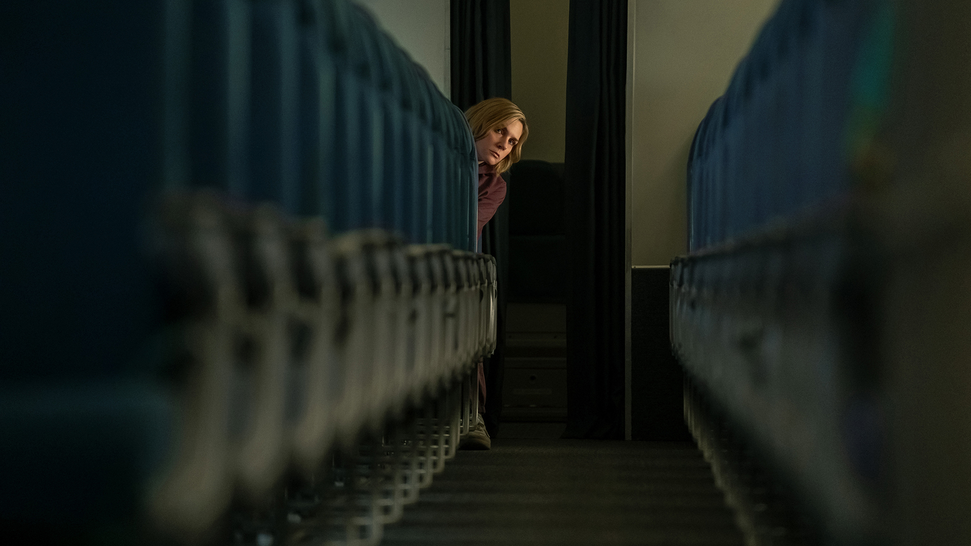 Carol leaning out from the back row of a plane in Pluribus episode 3