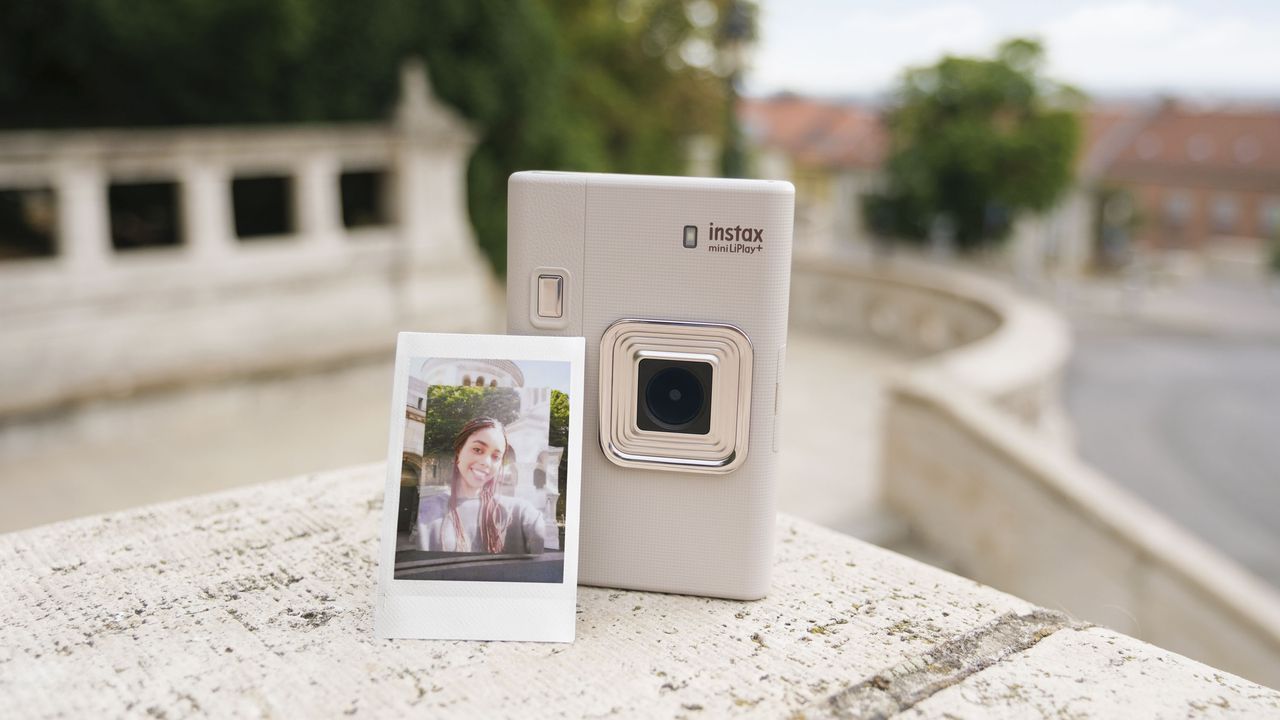 Fujifilm Instax mini LiPlay+ hybrid instant camera stood on marble steps with instant print propped against it