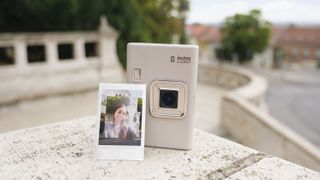Fujifilm Instax mini LiPlay+ 混合即時相機放置在大理石台階上,上面支撐著即時打印照片