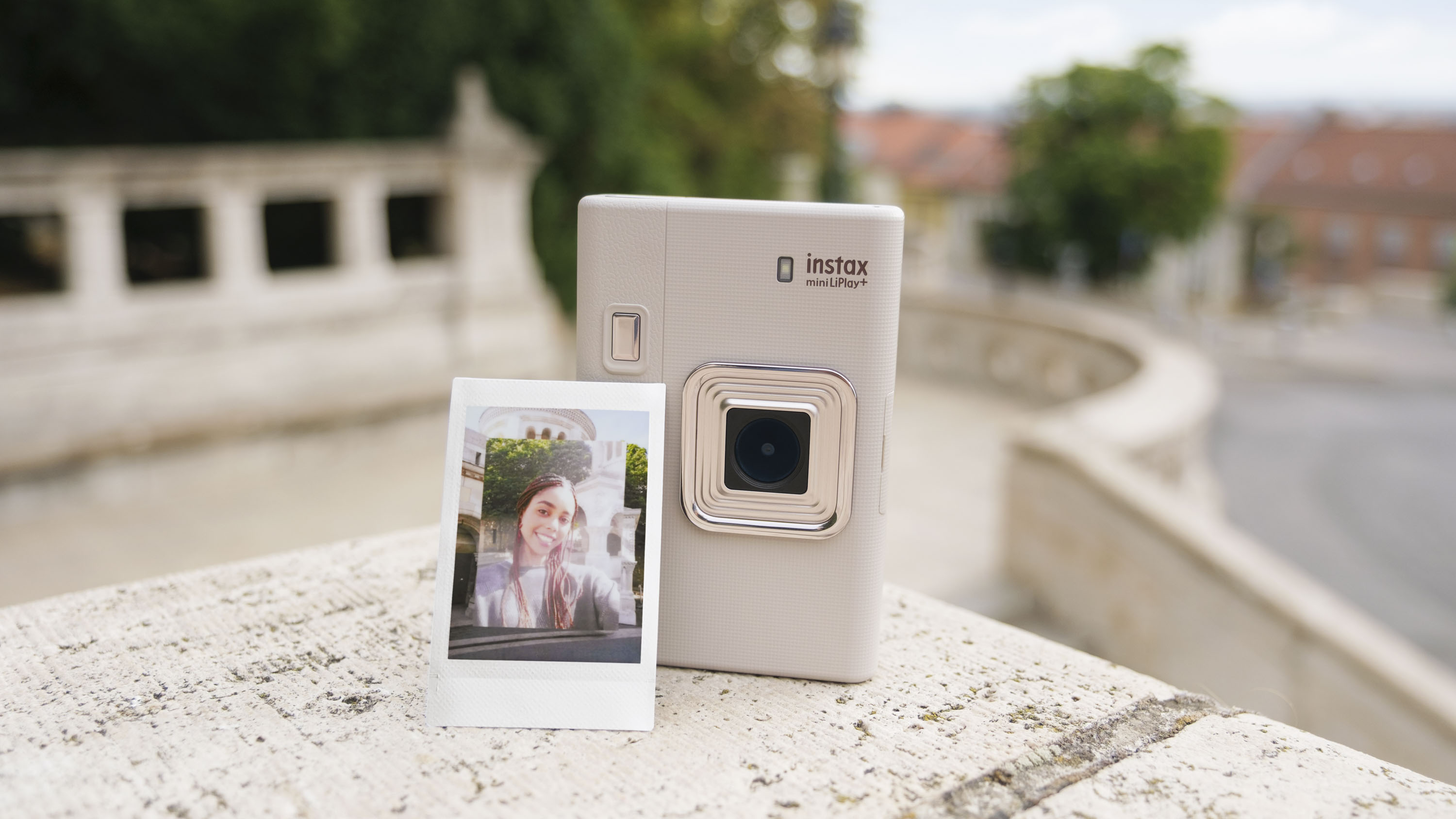 Fujifilm Instax mini LiPlay+ hybrid instant camera stood on marble steps with instant print propped against it