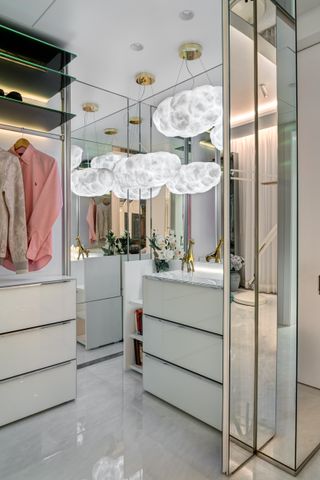 white luxury closet with mirrors and statement lighting