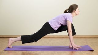 Woman performing low lunge flexibility exercise at home