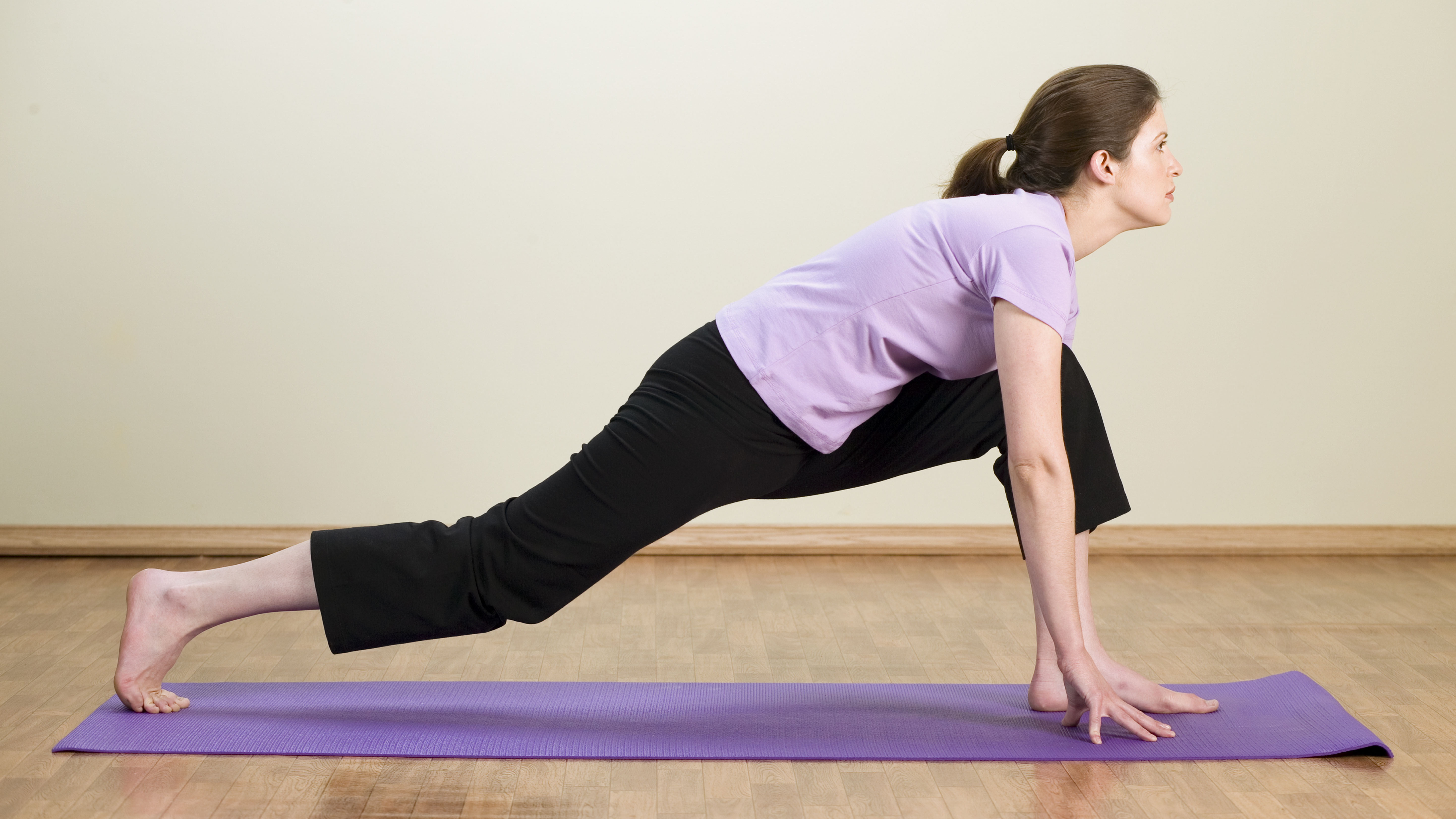 Mujer realizando ejercicio de flexibilidad de baja estocada en casa