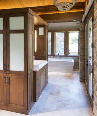 A bathroom with large central vanity unit made from warm wood