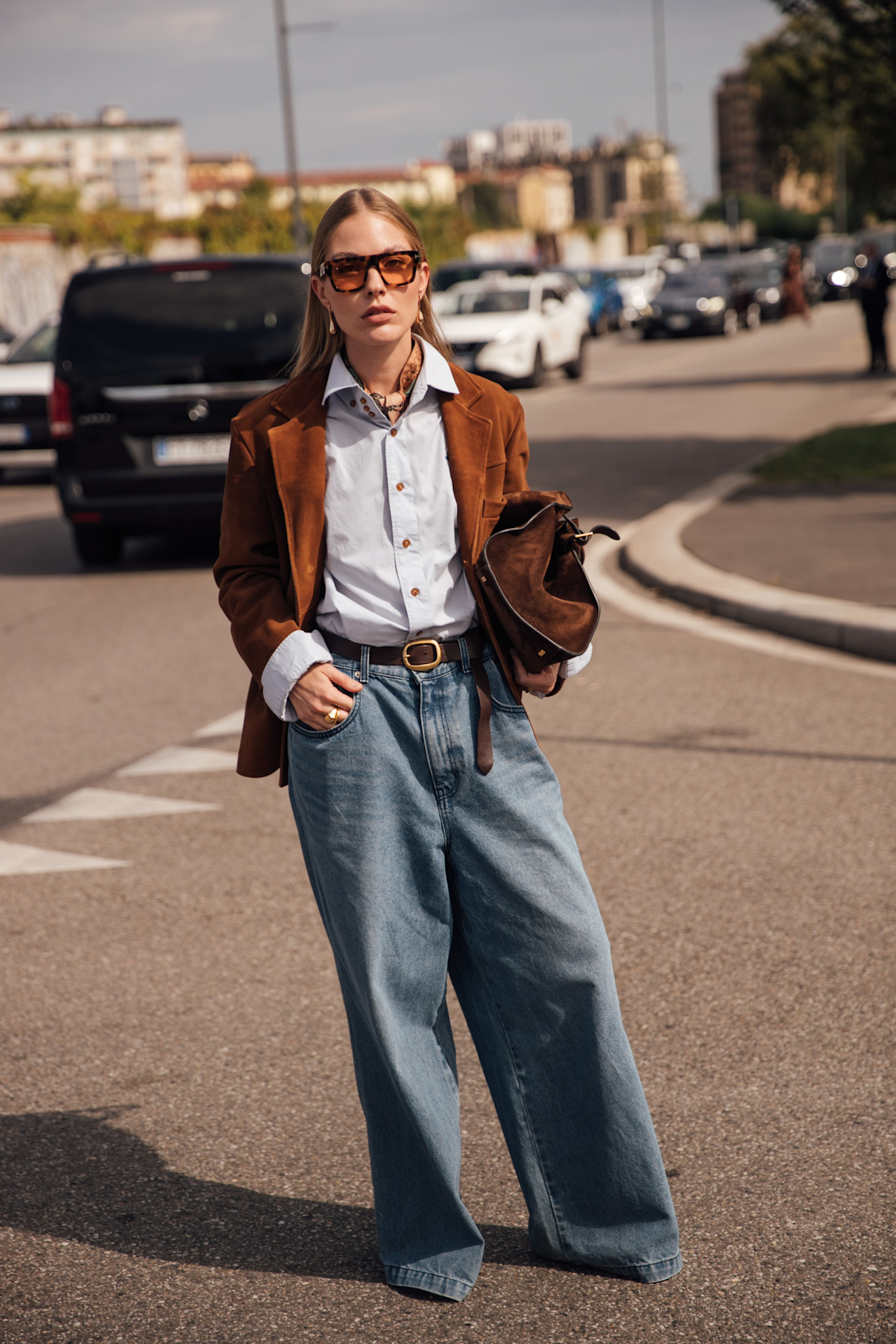 woman wearing suede jacket, button-down shirt, jeans, and heels