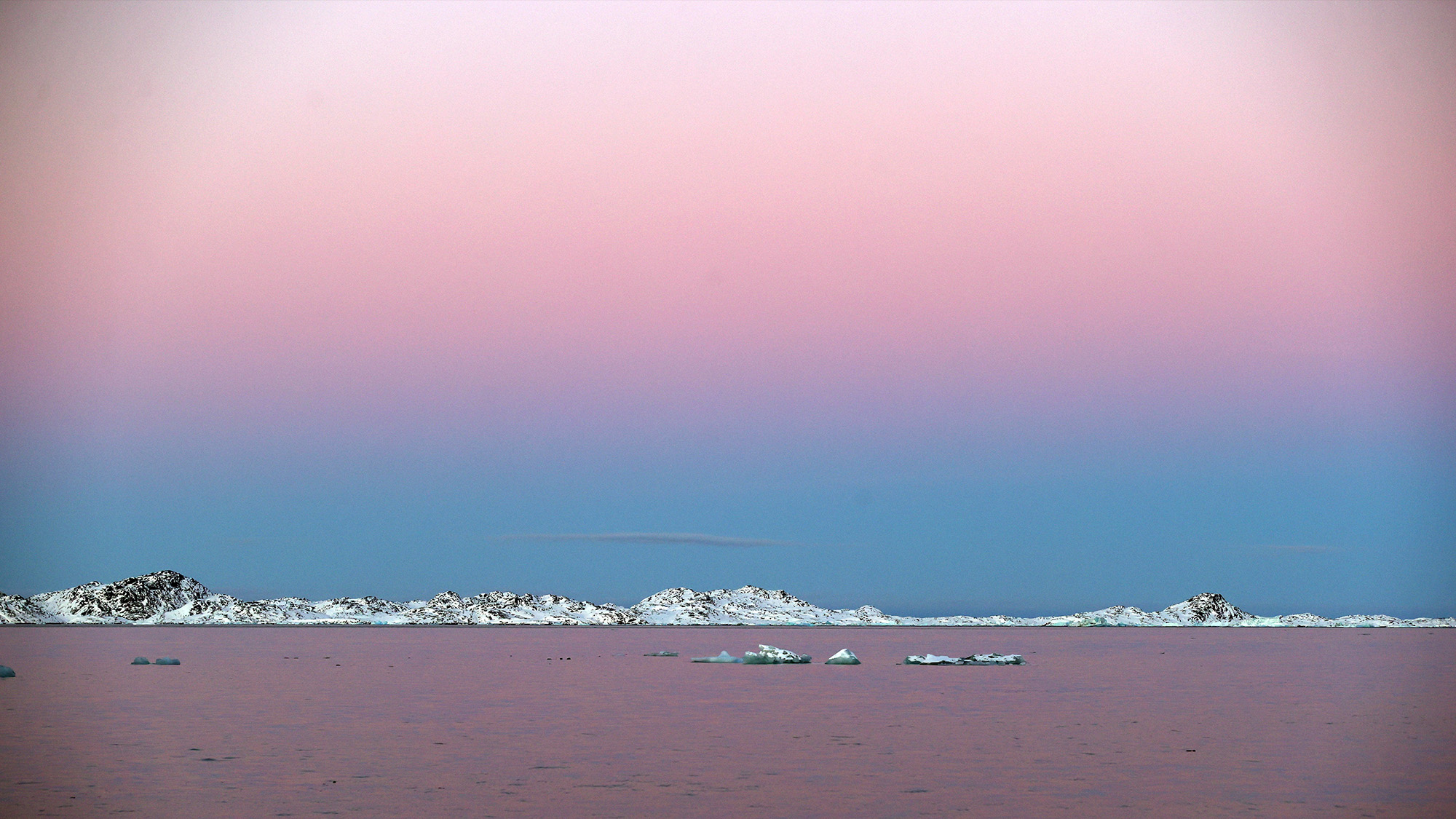 The sky appears bright pink over a violet sea near Nuuk, Greenland