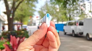 Skullcandy EcoBuds in light blue with reviewer holding a single bud between fingertips