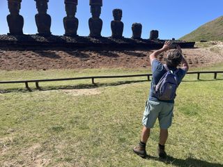 a man looks at some statues lined up against a blue sky as eclipse chasers gather for the annular solar eclipse.