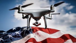 A camera drone sitting on a US flag, in front of a blue sky