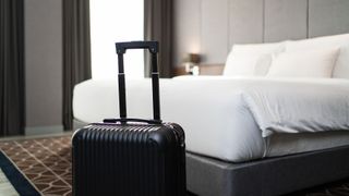 Suitcase next to a hotel bed