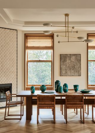 Wooden chairs surround a dining table with an assortment of blue-green ceramics