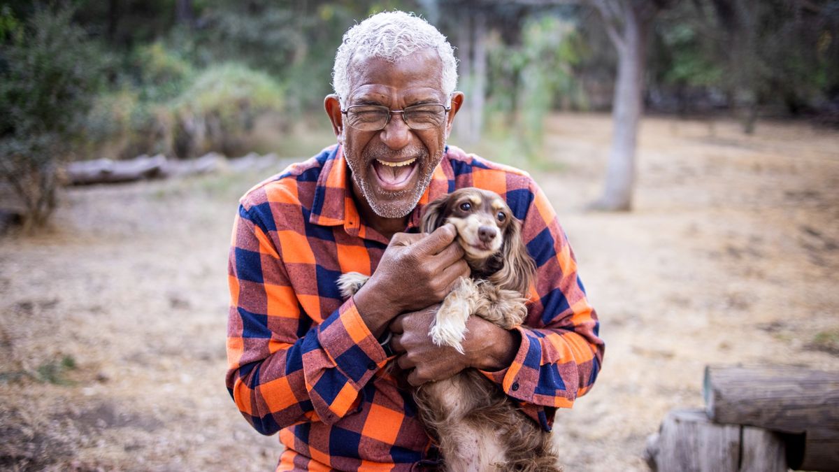 Man laughing while holding long haired dachshund outdoors