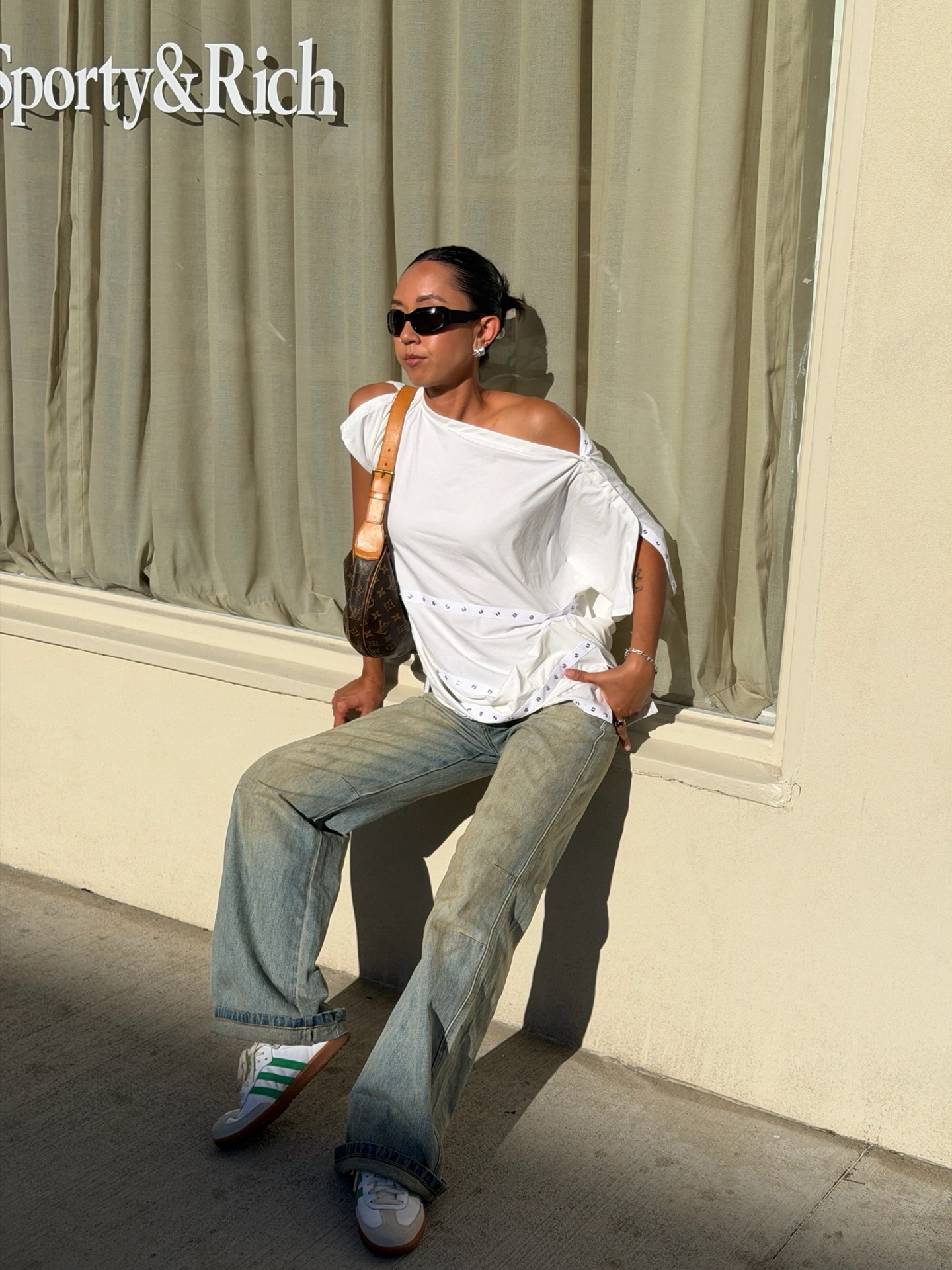 @shhtephs wearing Adidas sneakers, jeans, a white top, and a shoulder bag