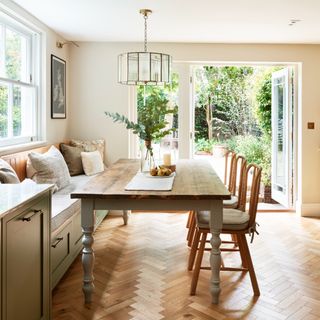 Wooden dining table and nook with chairs, double doors leading to backgarden