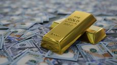 Gold bars sit on top of scattered cash.