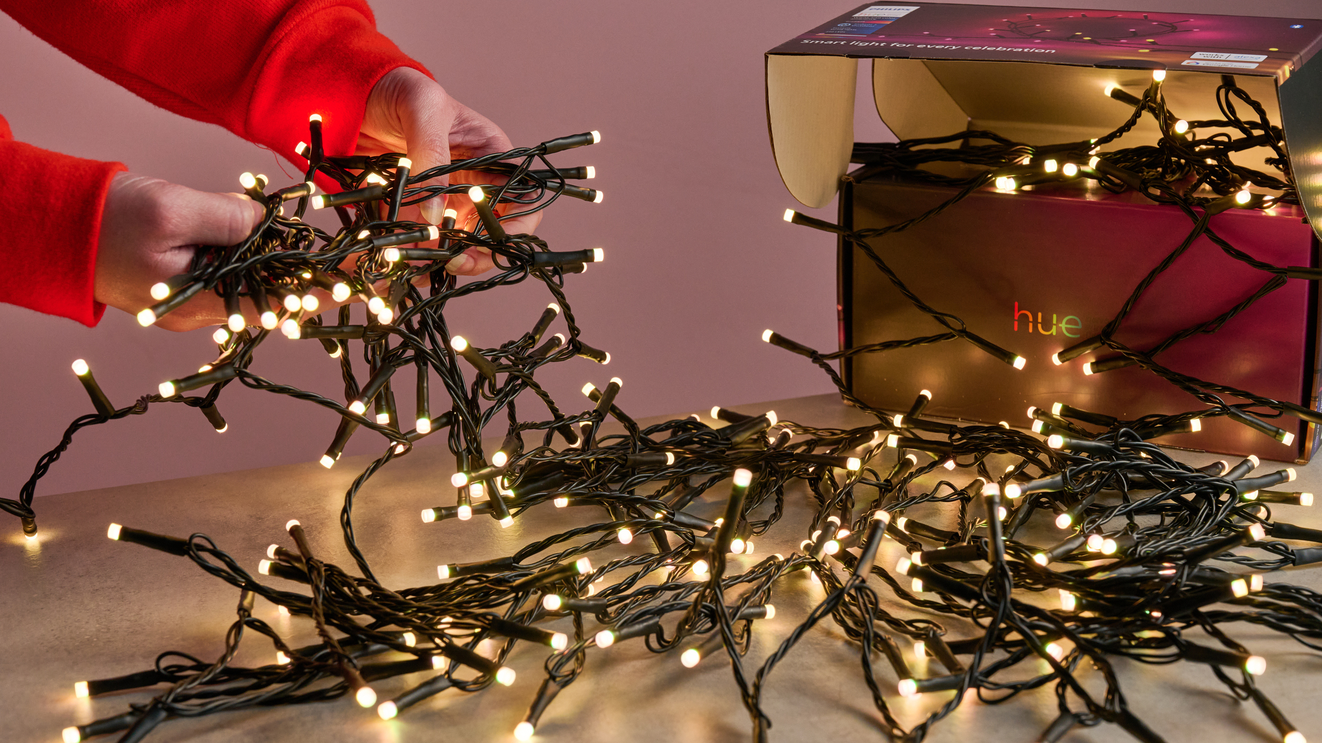 A woman is picking up the Philips Hue Festavia String Lights from a table.