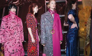 Models wear bicolour felt coat, pink scarf and printed coat with long neck jumper underneath, long bicolour dresses and accessories holders