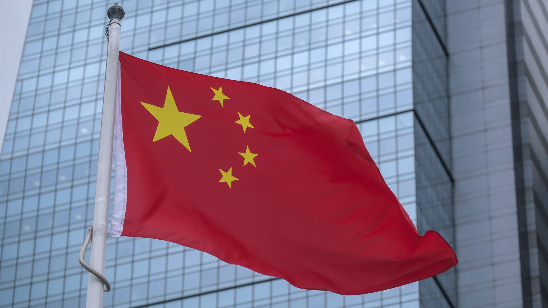 A Chinese flag flying in front of a skyscraper