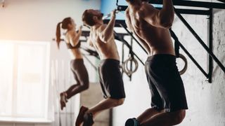 Three people in a row doing pull-ups
